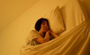 mulher deitada em cama com luz amarela