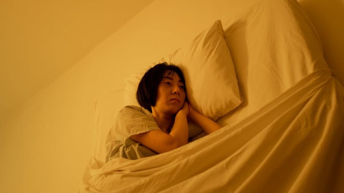 mulher deitada em cama com luz amarela